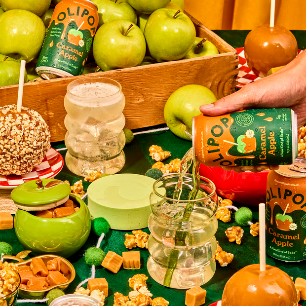 Green and caramel apples with Olipo Caramel Apple beverages, popcorn, and caramel candies arranged on wooden surface.